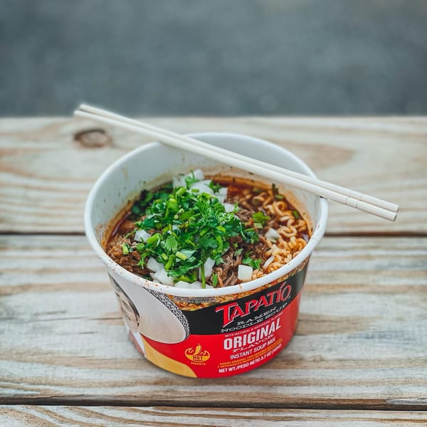 Tapatio ramen noodle soup with beef, cilantro, and diced onions, with chopsticks on top.