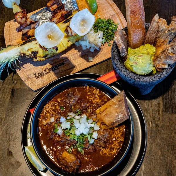 Mexican birria ramen, grilled pineapple with pork, and guacamole with chicharrones from Los Compas.